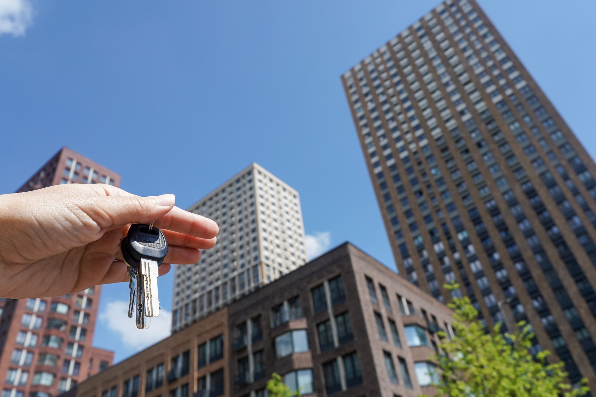 Wohnungsschlüssel mit einem neuen modernen Wohngebäude im Hintergrund